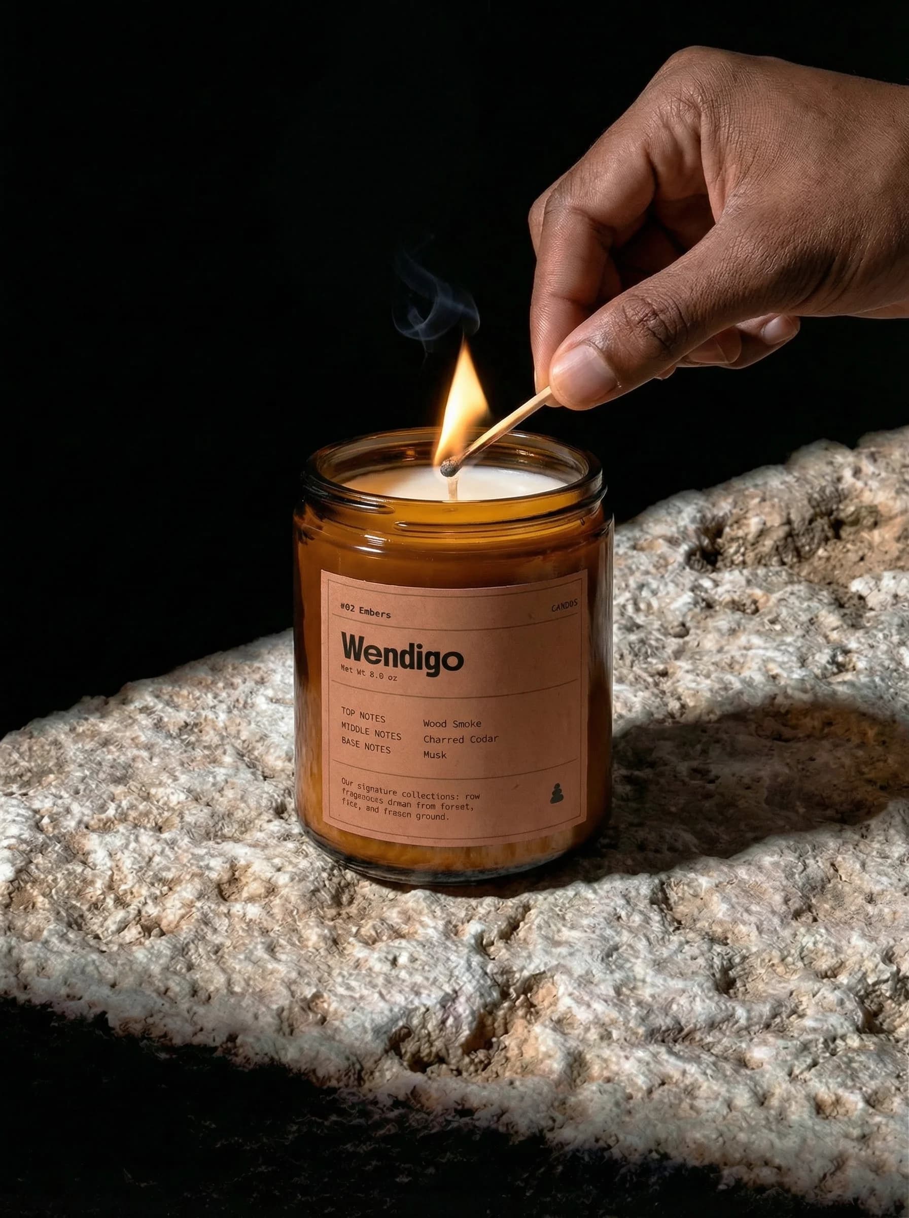 Hand lighting Wendigo Embers candle on natural stone